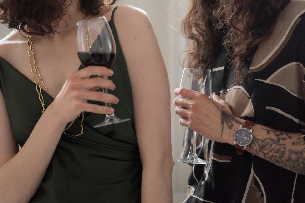 A couple drinking wine and wearing trendy clothes, the man wearing a luxury watch