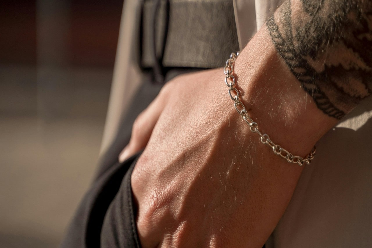 A closeup of a person’s wrist wearing a simple chain bracelet.