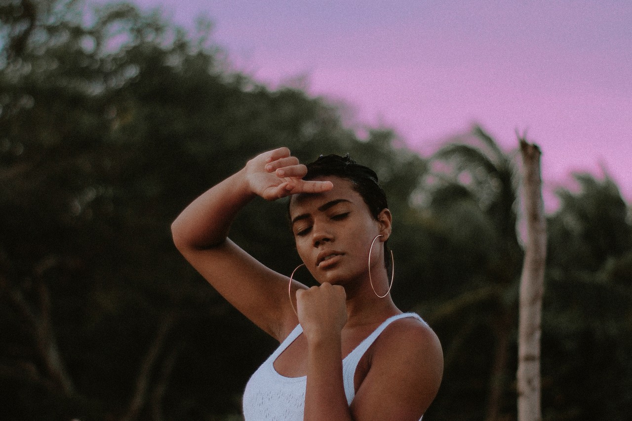 A young woman at dusk wearing thin yet bold hoop earrings.