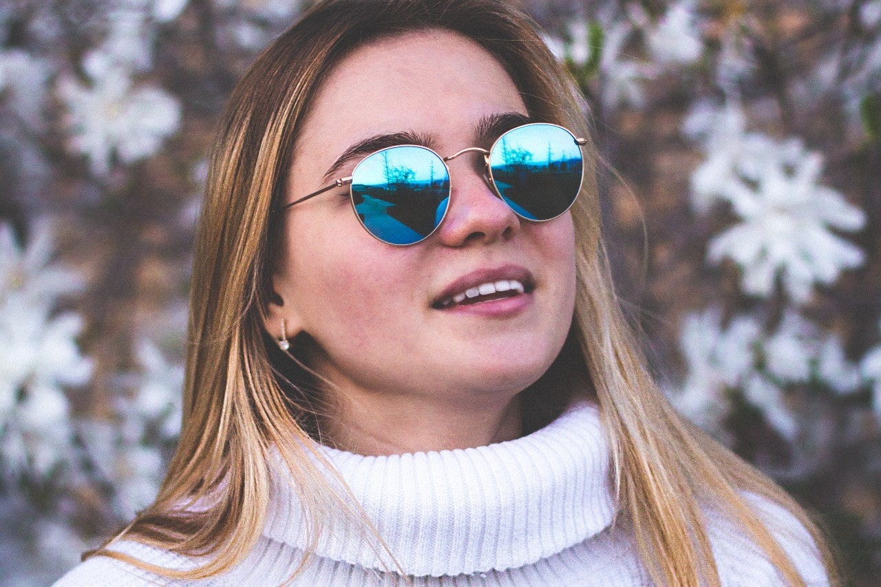 A comfortably dressed young woman wearing diamond huggie earrings.