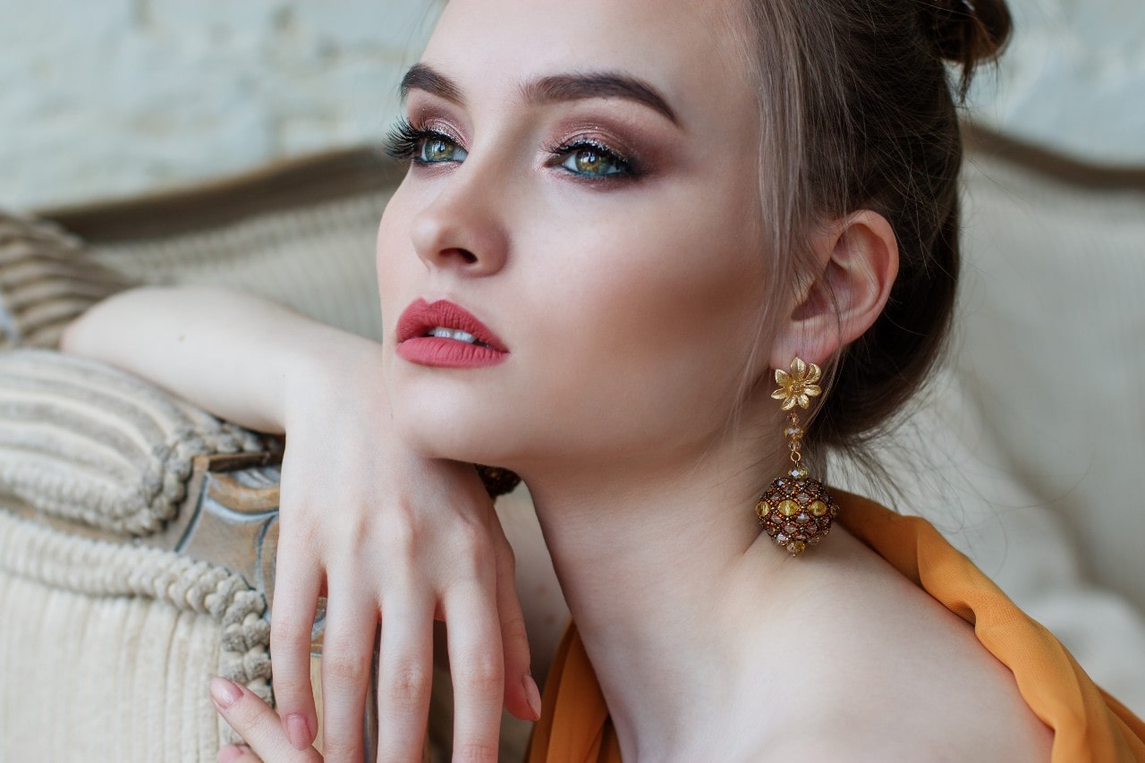 A close-up of a pretty young woman wearing ornate earrings.