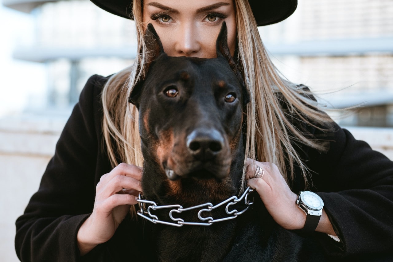 a woman holding her dog’s collar and wearing a silver and black watch