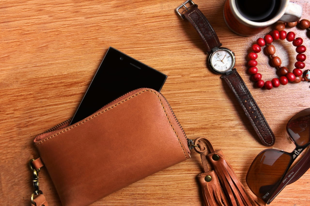 Watch with wallet, bead bracelet, coffee and sunglasses on a wooden table